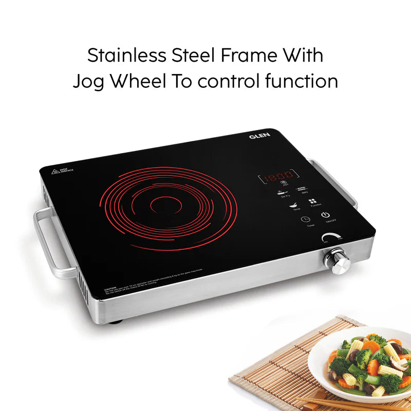 Induction cooktop with stainless steel frame and jog wheel, next to a plate of food on a white background.
